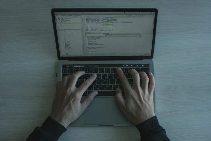 Close-up of a developer's hands writing code on a laptop keyboard