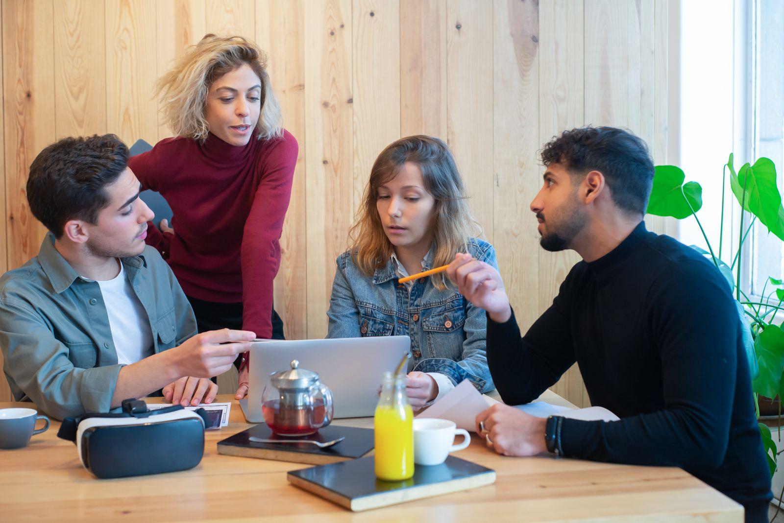 A diverse team collaborating with laptops around a table in a modern office