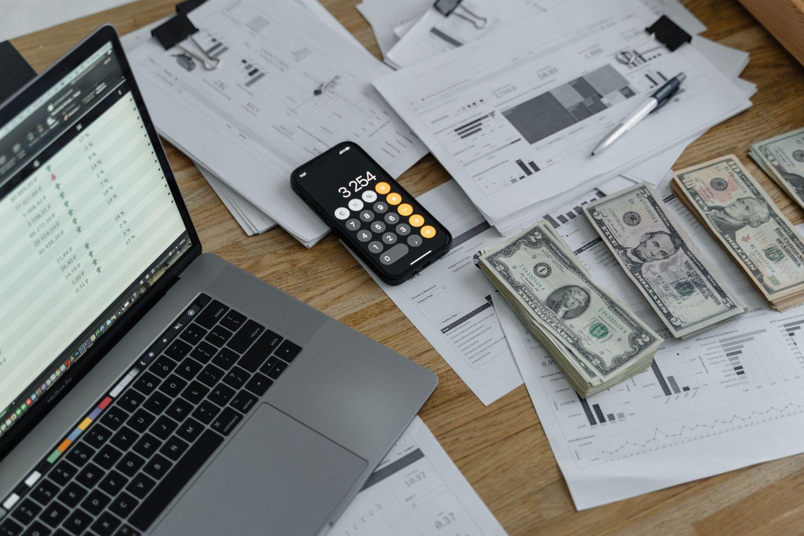 Banknotes, a calculator, and financial documents laid out on a desk