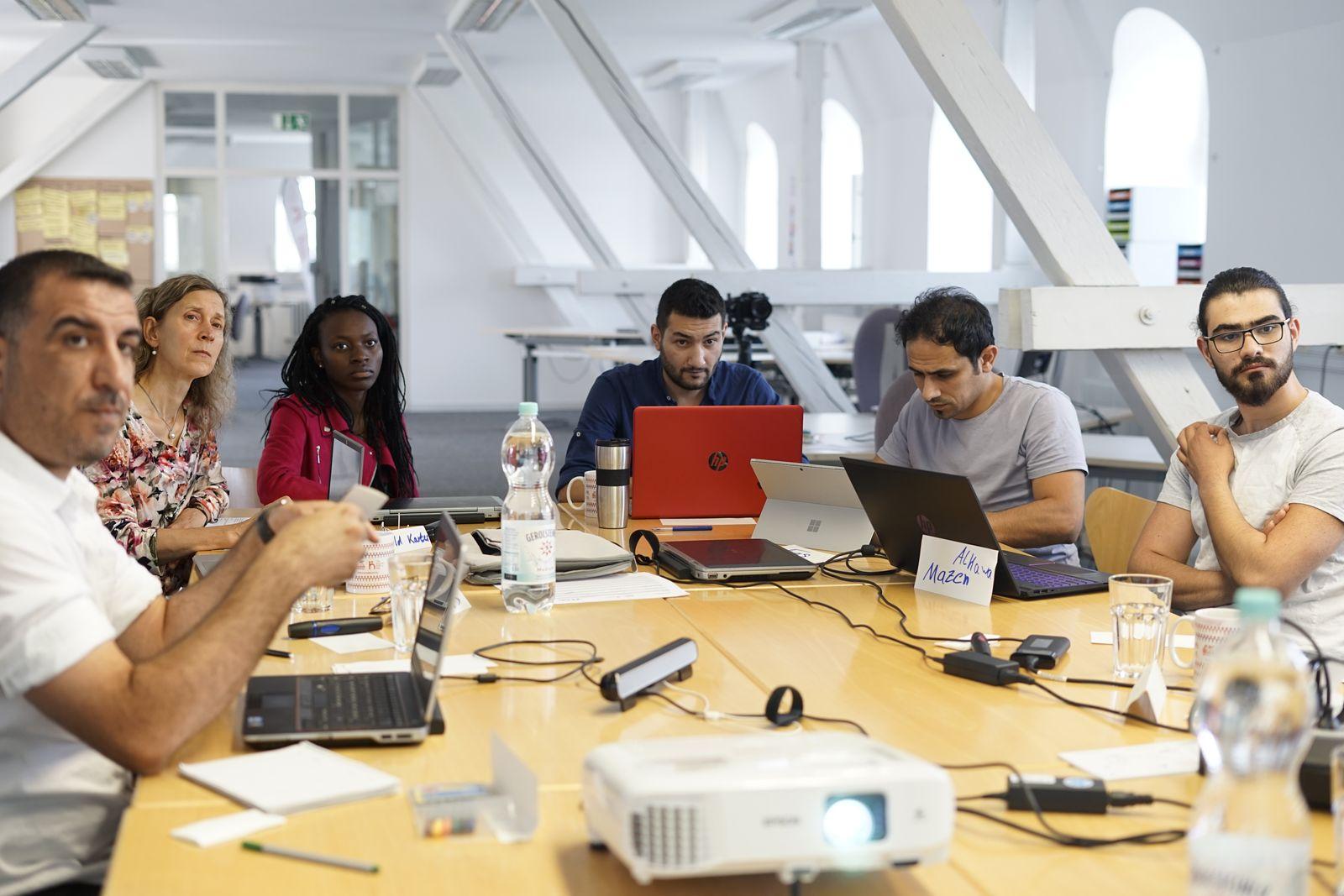 A small team collaborating around laptops at a shared table in a modern office